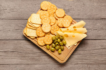 Platter with crunchy crackers and cheese on wooden background