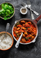 Delicious served lunch - meatballs, beans in tomato sauce, rice and green salad on a dark background, top view