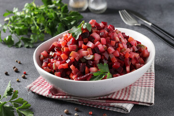 Traditional Russian salad Vinaigrette of beets, potatoes, carrots, beans, pickles, onions and vegetable oil on gray background. Vegetarian food