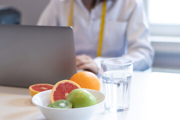 dietitian woman working with her computer and an office with mixed fruit and water on the table