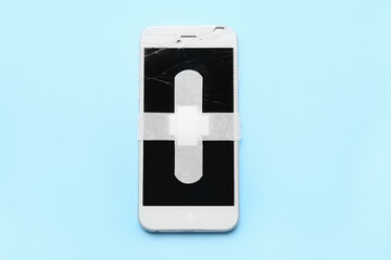 Mobile phone with medical plasters on pink background