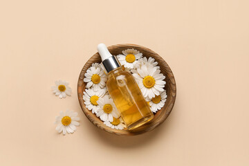 Bowl with chamomile flowers and bottle of essential oil on color background