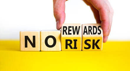 No risk or rewards symbol. Businessman turns wooden cubes and changes words 'no risk' to 'no rewards'. Beautiful white background. No risk or rewards and business concept. Copy space.