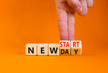 New day and start symbol. Businessman turns wooden cubes and changes words 'new day' to 'new start'. Beautiful orange table, orange background. Copy space. Business, new day and start concept.