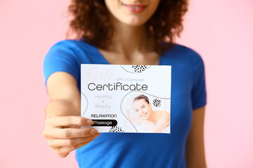 Pretty young woman with gift certificate on pink background, closeup