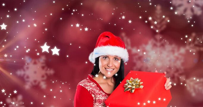 Animation of stars falling over happy caucasian woman wearing santa hat keeping present