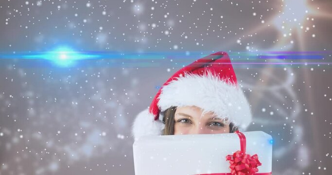 Animation of snow falling over happy caucasian woman wearing santa hat keeping present