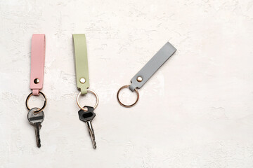 Keys with leather keychains on light background