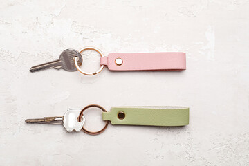 Keys with leather keychains on light background