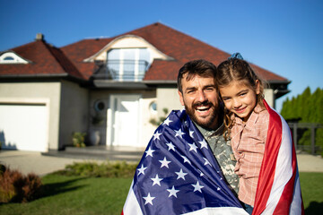 Portrait of father soldier in uniform on military leave holding his lovely daughter in front of...