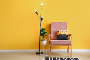 Glowing lamp and armchair in interior of room with color wall