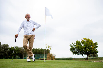Portrait of an active senior man playing golf at the golf course and enjoying free time outdoors. - Powered by Adobe