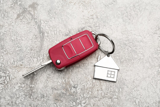 Red car key with house shape keychain on grunge background