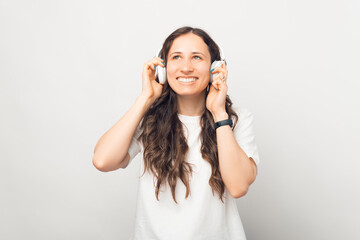 Fototapeta premium Joyful young smiling woman is trying wireless earphones over white background.