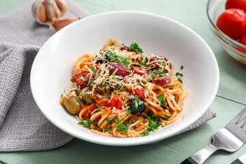 Bowl of tasty Pasta Puttanesca on white wooden background
