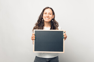 Naklejka premium Smiling woman is holding a small blackboard with space for your text.