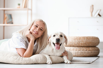 Mature woman with cute Labrador dog lying on pet bed at home