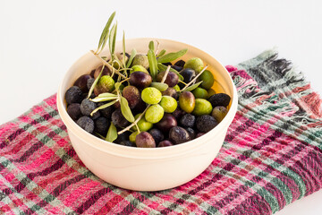 New crop mixed olives and fresh,green leaves in bowl on white background with fabric cloth ,harvest concept