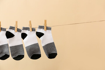 Many socks hanging on rope against color background, closeup