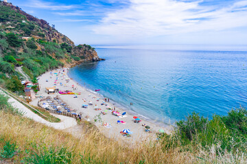 Pequeña cala en forma de herradura con acantilados a su espalda un día soleado de verano en...