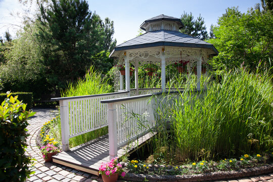 White gazebo in the park surrounded by tall grass