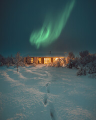 Northern Lights and Aurora Borealis over Winter landscape with wooden house under a beautiful...