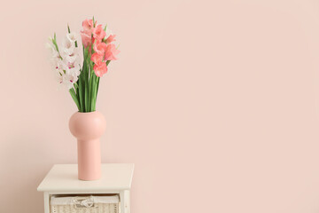 Vase with gladiolus flowers on table in room