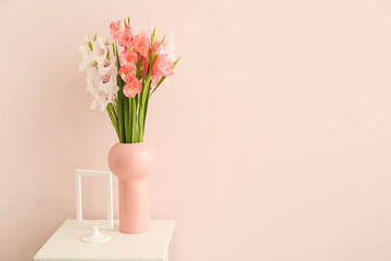 Vase with gladiolus flowers on table in room