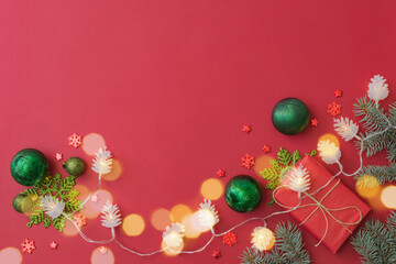 Naklejka na ściany i meble Flat lay frame with fir branches, christmas baubles decoration and gift box on a red background