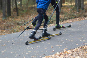 Men ride roller skis in the autumn Park.