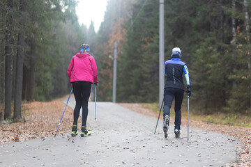 Women ride roller skis in the autumn Park.