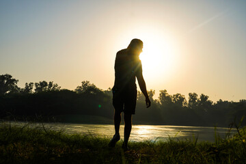 silhouette of a boy in park near sun and river - health concept