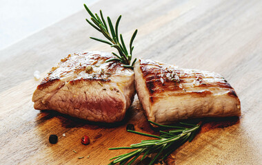 Schweinefilet gegrillt mit Rosmarin. Filetsteak grilled with rosemary on wooden table