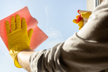 Contemporary man washing windows at home, Office shirt with rolled up sleeves, pink cloth, yellow rubber gloves, Concept of home cleaning also performed by men