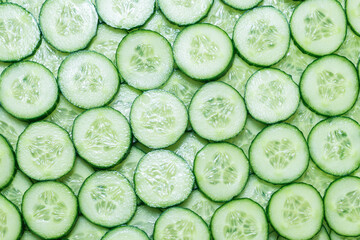Fresh green slices of cucumber as background.
