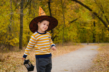 A preschool boy walks with a lantern in the Halloween autumn forest