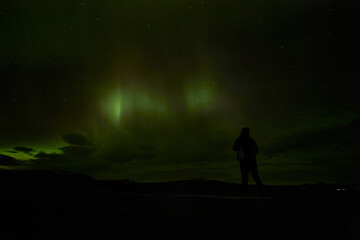 Obraz na płótnie Canvas Silhouette of woman watching night sky with aurora borealis