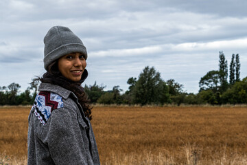 Beautiful shot of a Hispanic female in a gray hat posing in a forest during the rainy weather