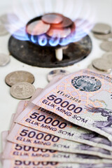 Burning gas stove burner and Uzbek money - sum banknotes. Pay for natural gas, bill, tariff. Growing tariffs for gas. Pile of coins and burning fire gas stove hob and money