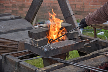 blacksmiths work with metal, heating it in a fire.