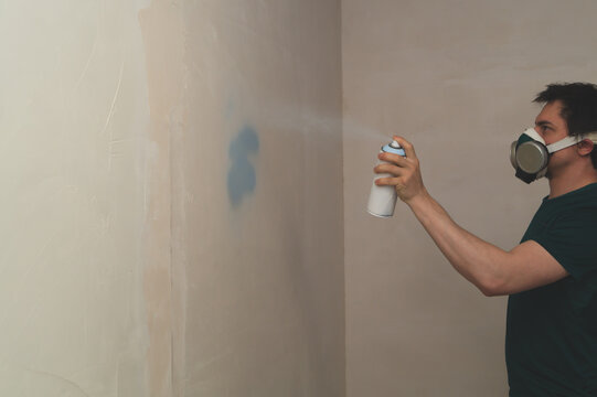 Man spraying paint on the wall. spray can in the hand. face in respirator
