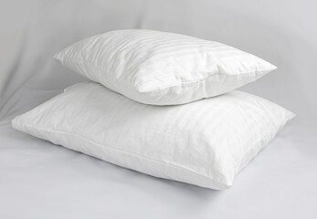 Two white pillows in striped cotton pillowcases. Satin jacquard bedding and accessories. Air soft pillows filled with swan down and bamboo