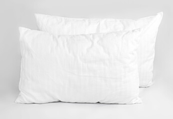 Two white pillows in striped cotton pillowcases. Satin jacquard bedding and accessories. Air soft pillows filled with swan down and bamboo