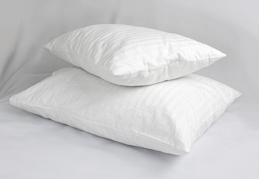 Two white pillows in striped cotton pillowcases. Satin jacquard bedding and accessories. Air soft pillows filled with swan down and bamboo