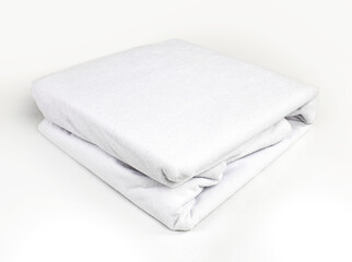 White, neatly folded terry waterproof mattress topper. Mattress covers. Protection of the bed from water and baby secretions. Production of mattress covers from cotton materials