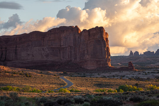 Winding road and giant rock formations at golden hour sunset in Arches National Park, Utah
