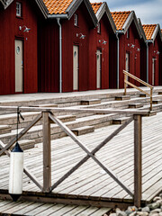 Row of Red boat houses in a marina with a wooden deck and railing