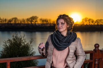 beautiful girl at sunset on the background of water in casual clothes