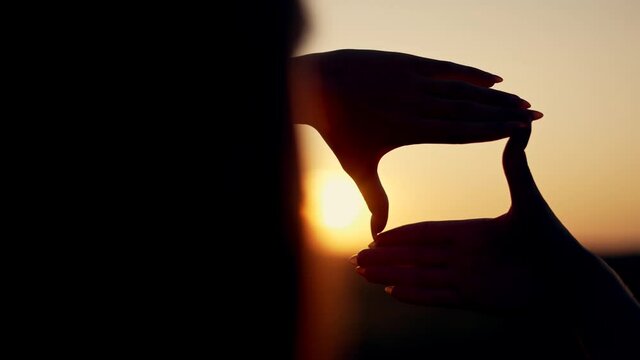 Business strategy. Girl folded her hands in frame at sunset. Silhouette of girl in natural park. Fingers at sunset. Work planning. Girl in field folded her hands into frame. Business planning concept.