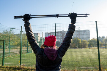A woman is engaged in Nordic walking near the stadion. Woman stretching in the park listening to...